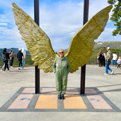 Martha Frankel is standing in front of a statue of golden wings to make it look like they're her wings