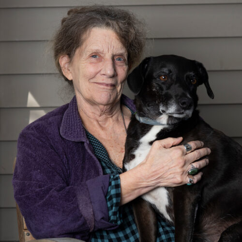 Author Abigail Thomas embracing her black and white dog